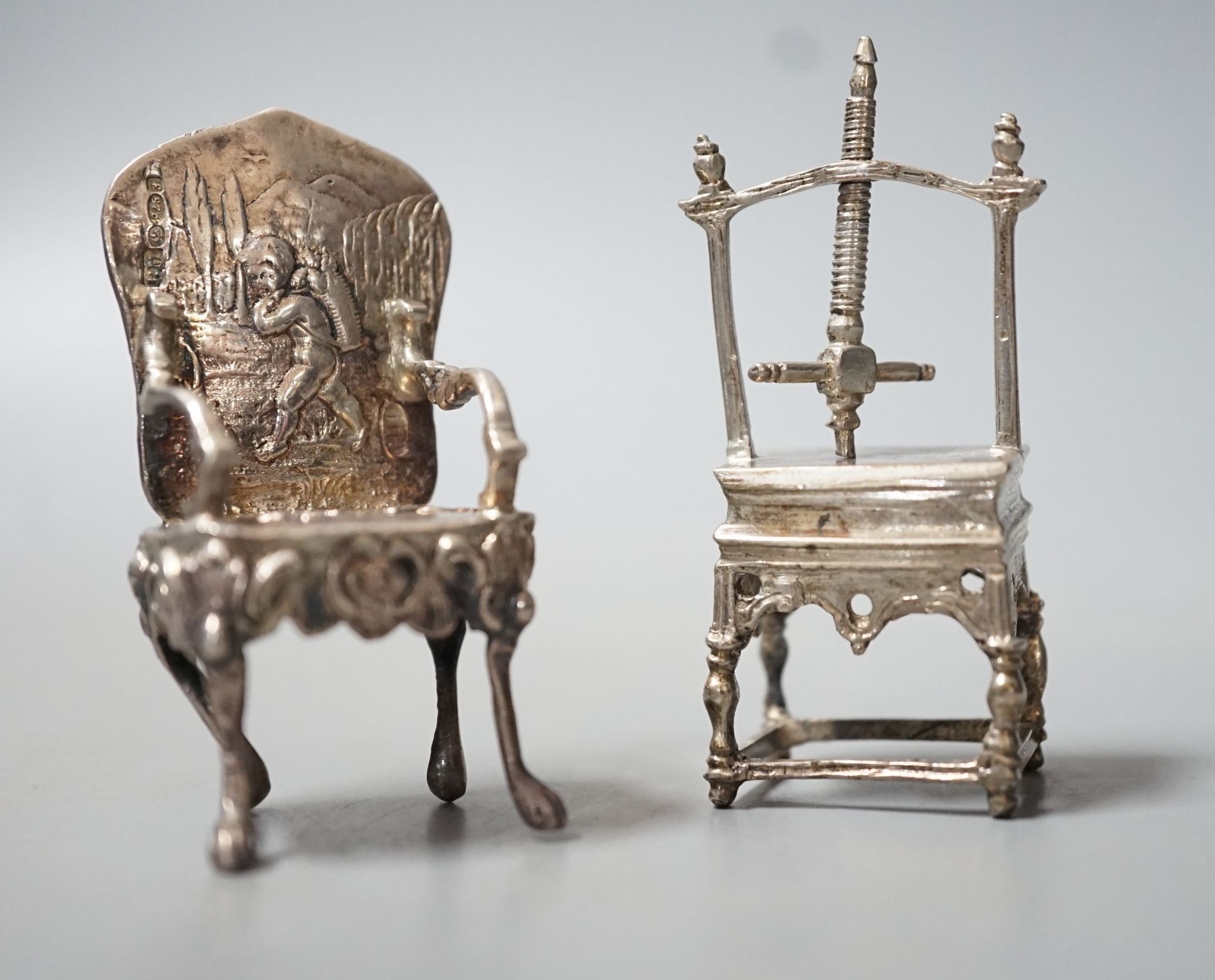 An Edwardian silver miniature model of an armchair, import marks for Glasgow, 1902, 64mm and a white metal model of a press.